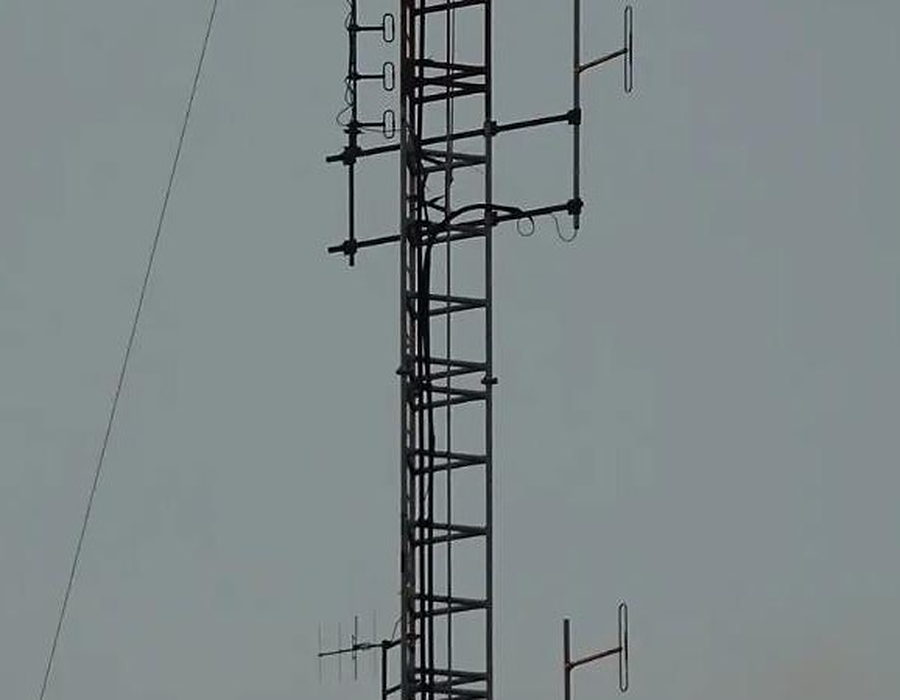 Guyed radio mast carrying antenna arrays against an overcast sky